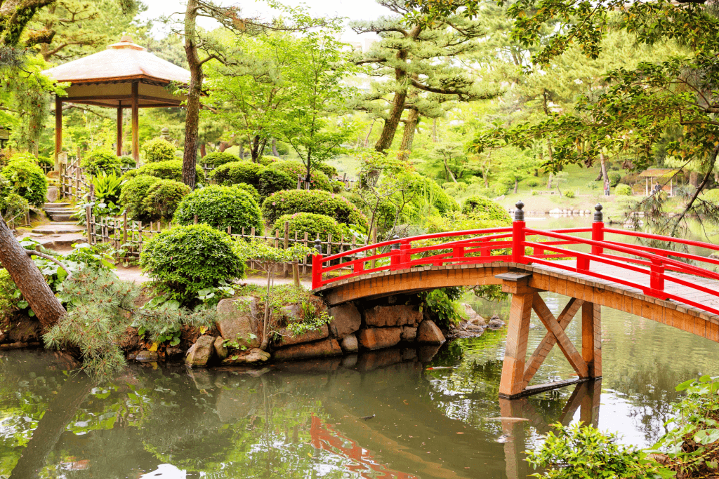 Shukkeien Garden in Hiroshima, there's a pond and red bridge.