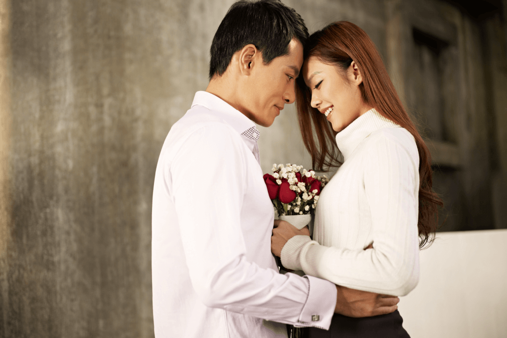 A man embraces a woman holding a Valentine's Day gift bouquet.