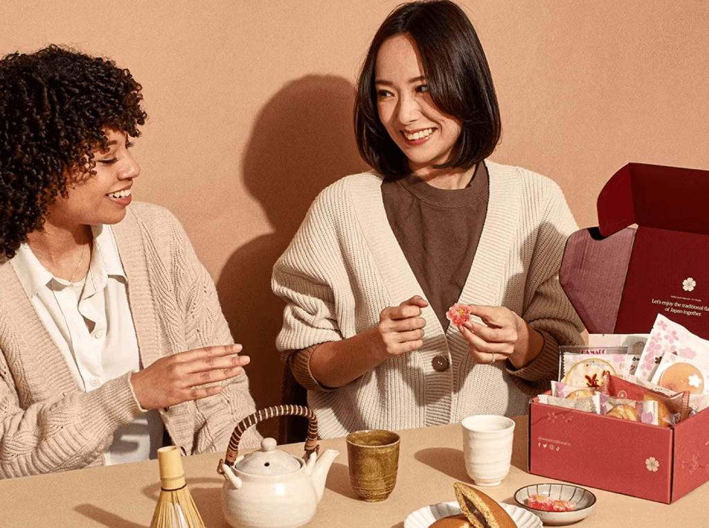 Two women enjoying Japanese snacks from the Sakuraco gift box for International Women's Day