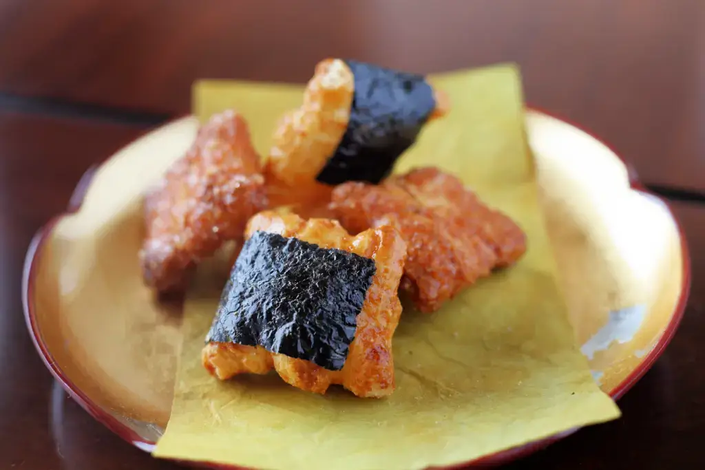 A plate of roasted rice crackers with seaweed on it.