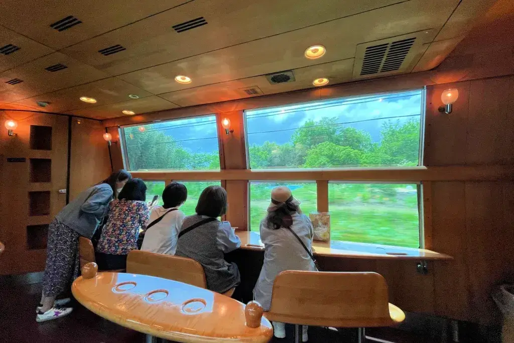 Four friends looking out the window on a luxury train ride in Japan.