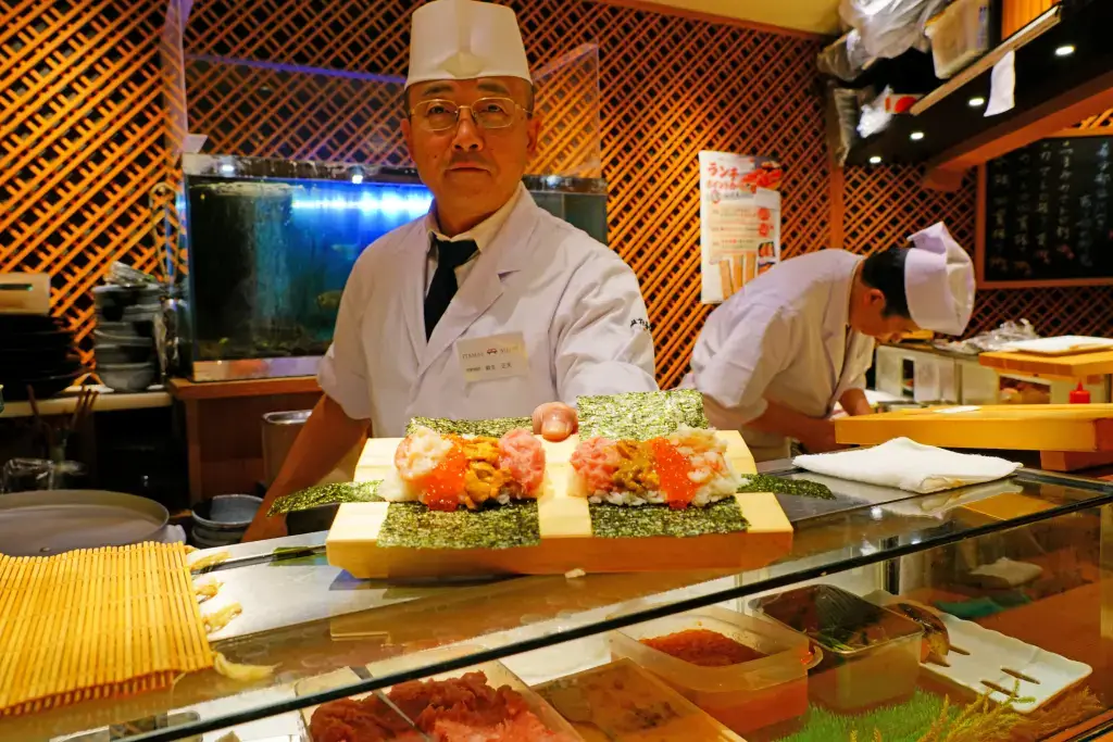 A chef presenting a sushi set to his customer.