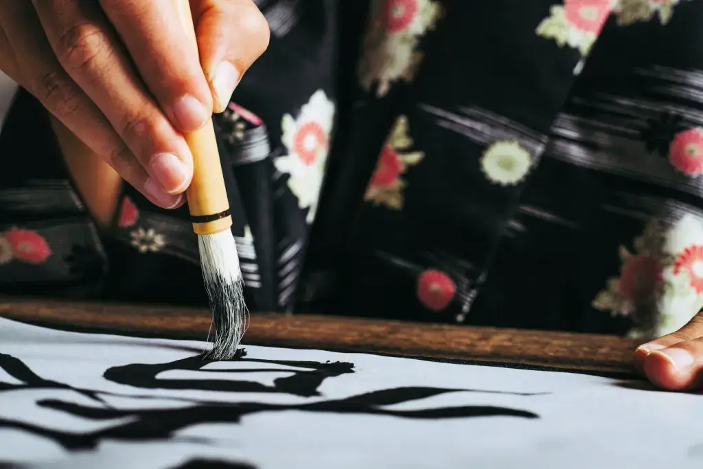 A person painting calligraphy, a form of Japanese art.