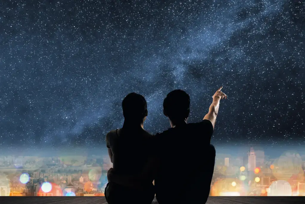 A silhouette of people pointing to the stars.