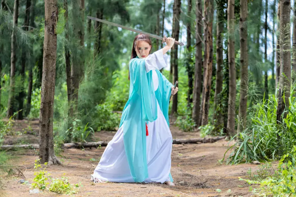 A female warrior in blue and white costume, training in a forest.