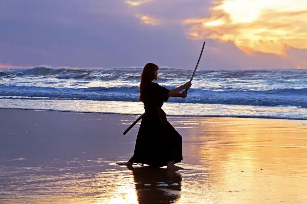 A female warrior doing swordplay training on the beach.