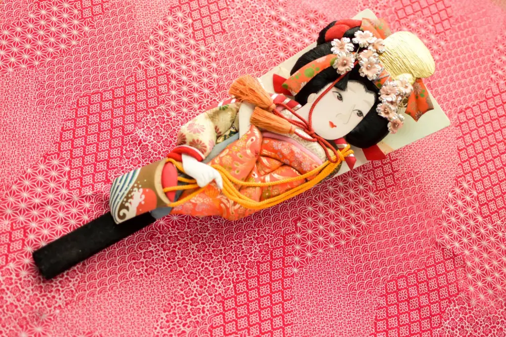 A hanetsuki paddle with a woman wearing a kimono on it.