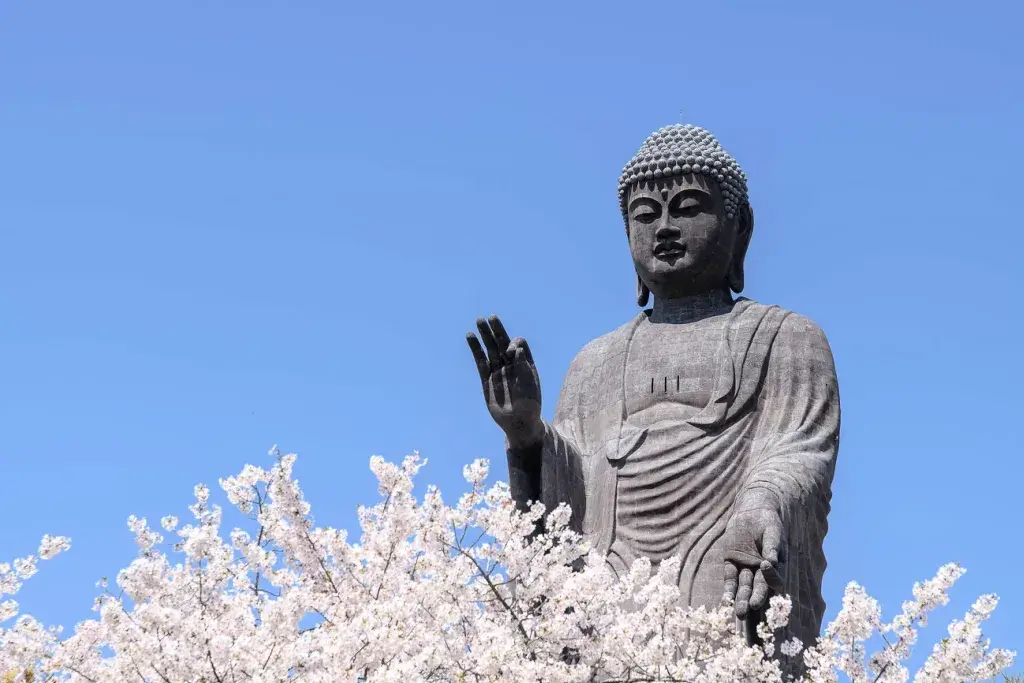 The Ushiku Daibutsu close to a cherry blossom tree.