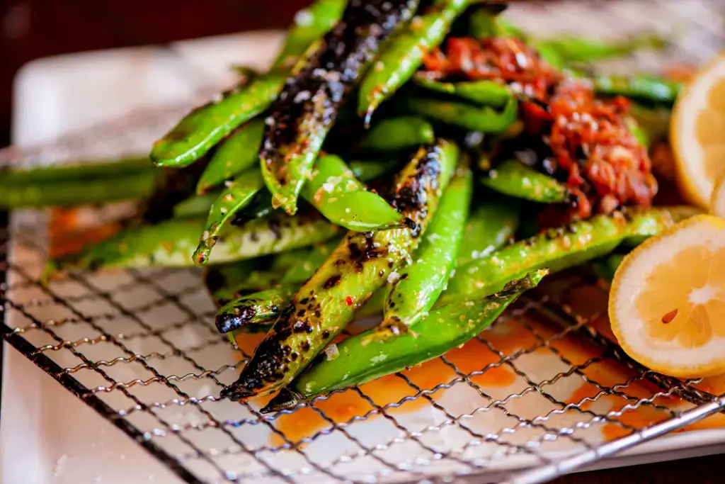 A bunch of seasoned edamame on a grill.