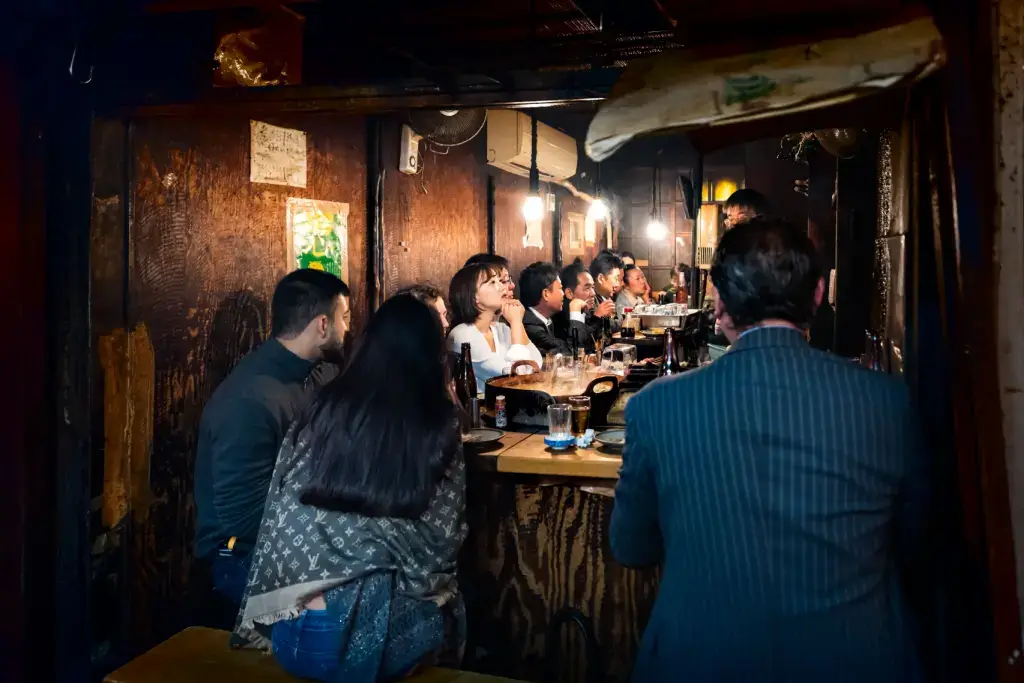 A bunch of people at the bar at an izakaya.