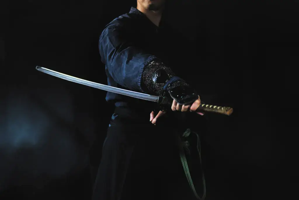 A samurai holding a sword in the dark. Their swords are prone to incorrect samurai facts.