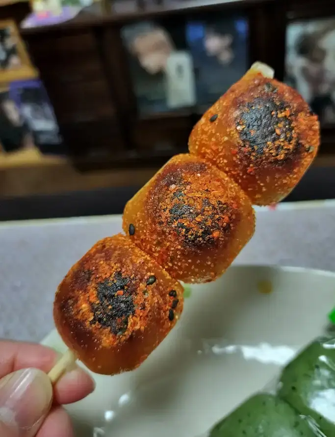 Grilled dango on a stick with shichimi on it.