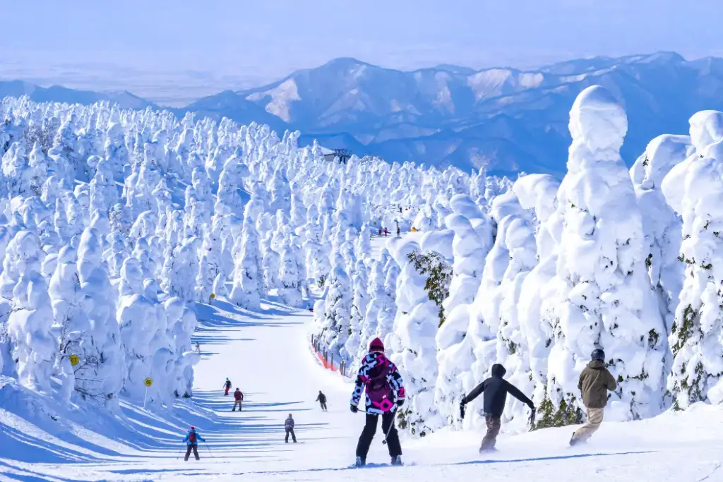 People skiing down a snowy hill at Zao Onsen Ski Resort, near Ginzan Onsen.