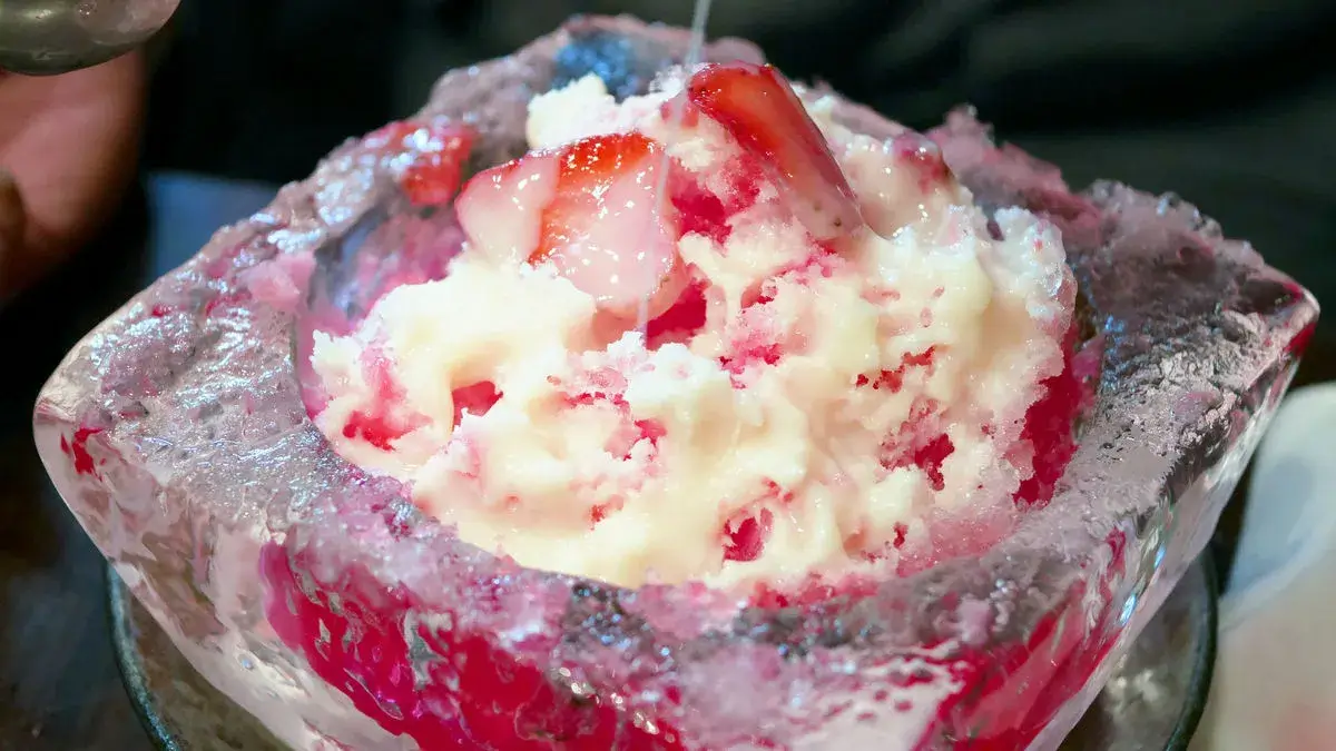 A bowl of strawberry kakigoori in a bowl made of ice.