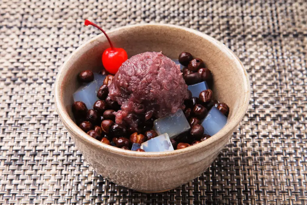 A bowl of mitsumame with a cherry and anko paste on top.