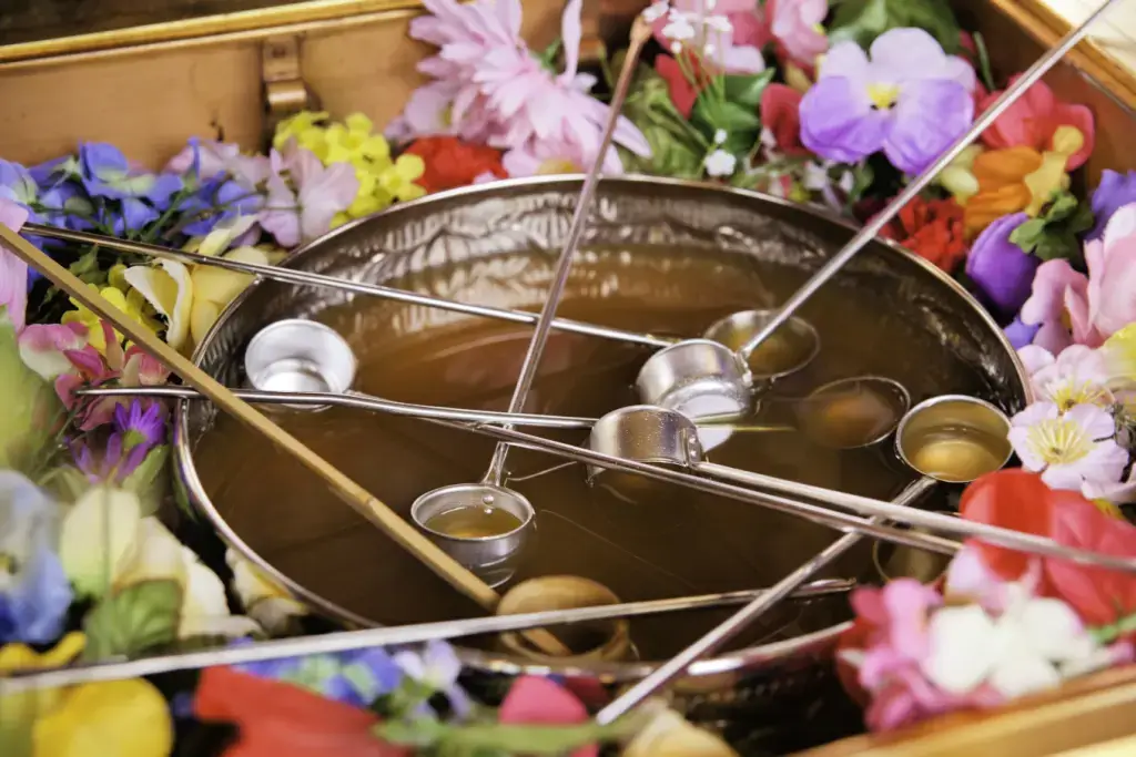 An arrangement of flowers surrounding a bunch of holy water ladles at a Hanamatsuri celebration. 