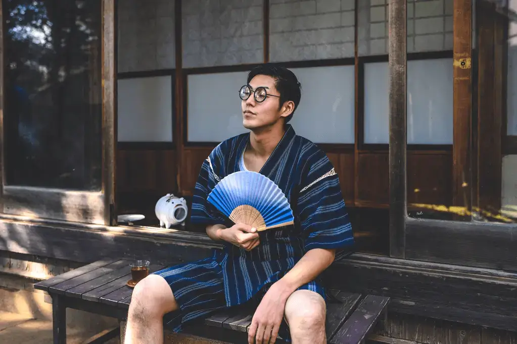 A man outside wearing glasses wearing a blue jinbei.