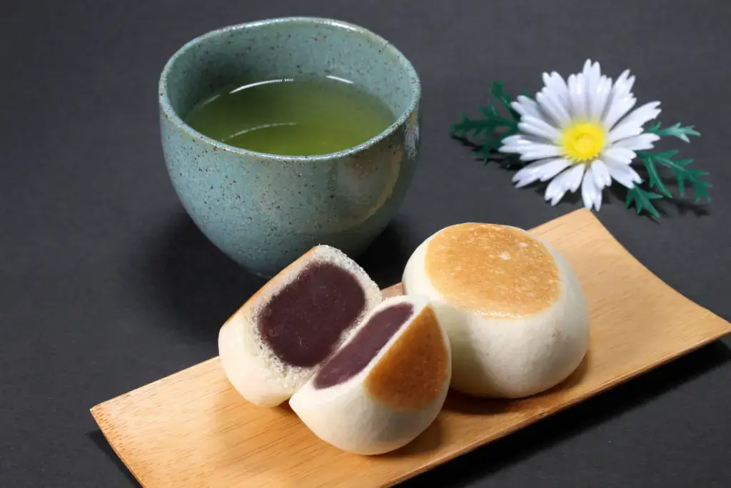 A plate of manju next to green tea.