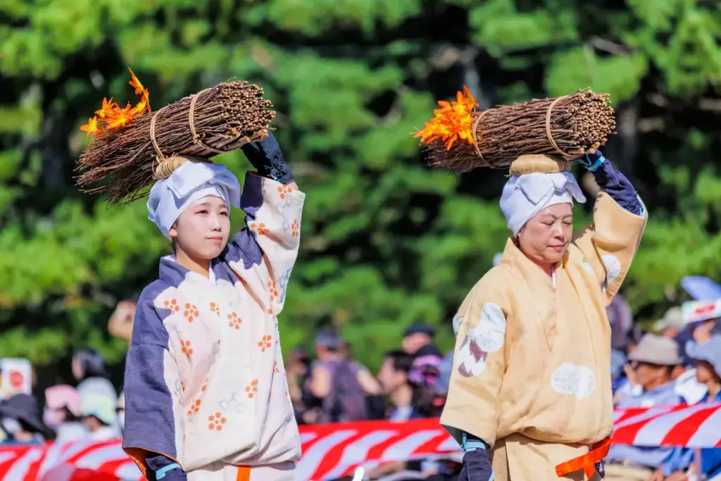 Two people carrying burning sticks at the Jidai Matsuri.