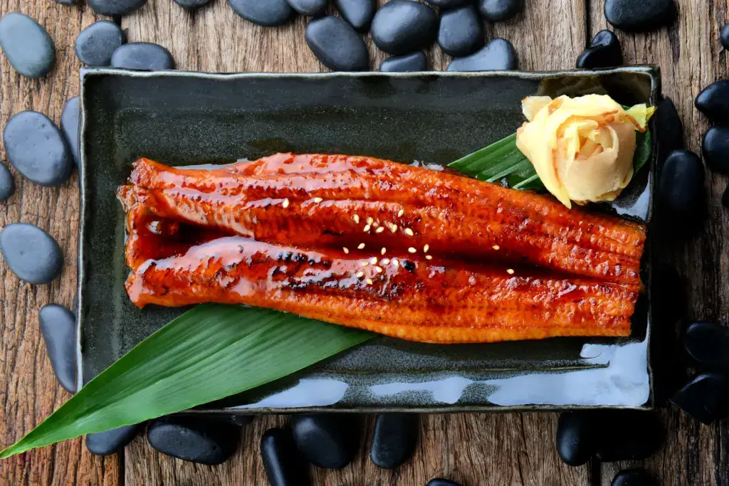A slice of grilled unagi with tare sauce on top.