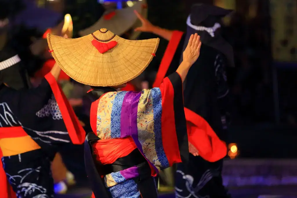 A dancer wearing colorful clothes and a large brim hat at the Nishimonai Bon Odori event.