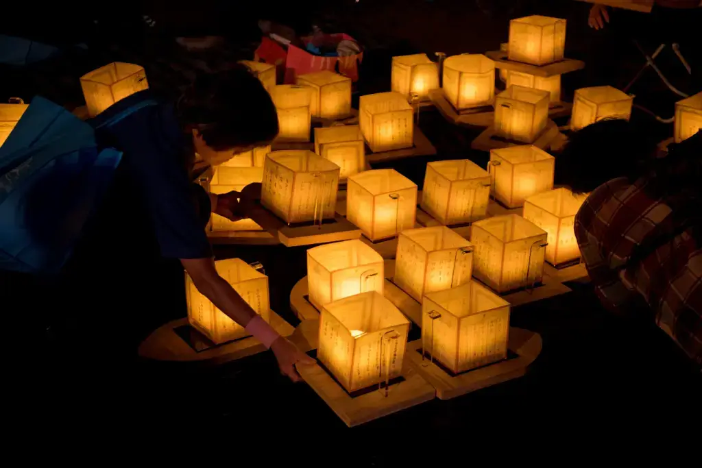 People lighting Obon lanterns at night.