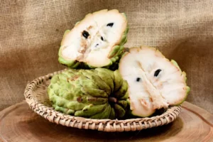 A basket of atemoya. It's green with white flesh and black seeds.
