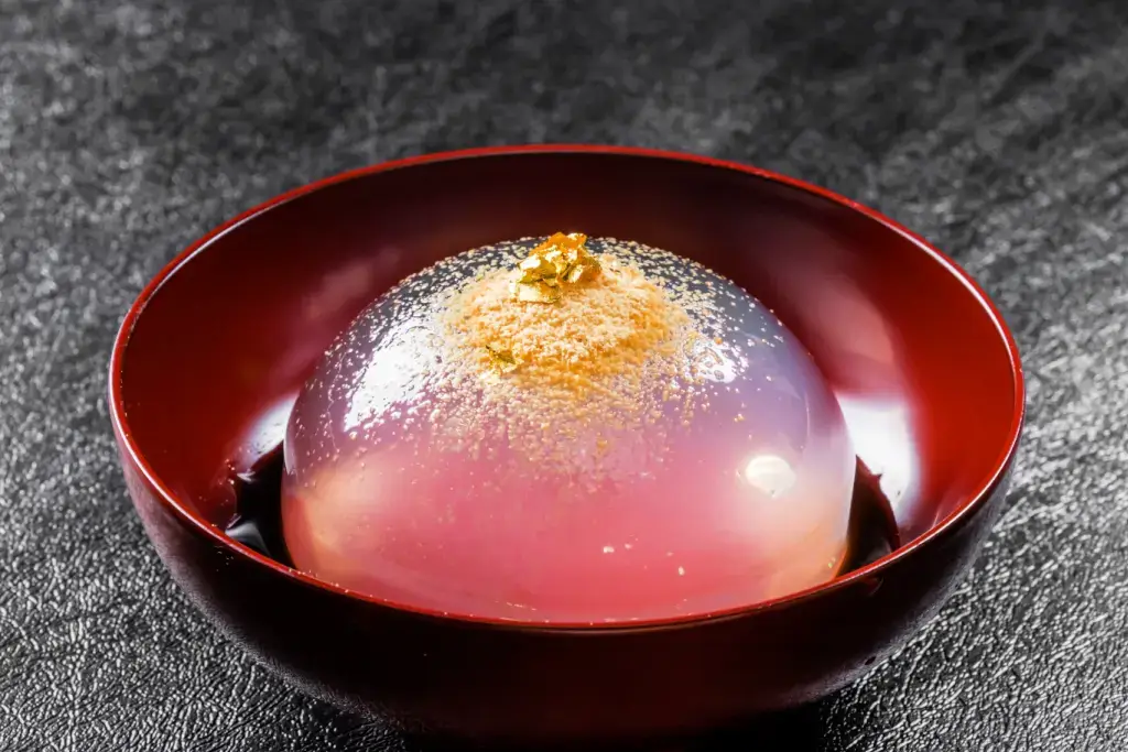 A raindrop cake with kinako powder and gold dust on top.