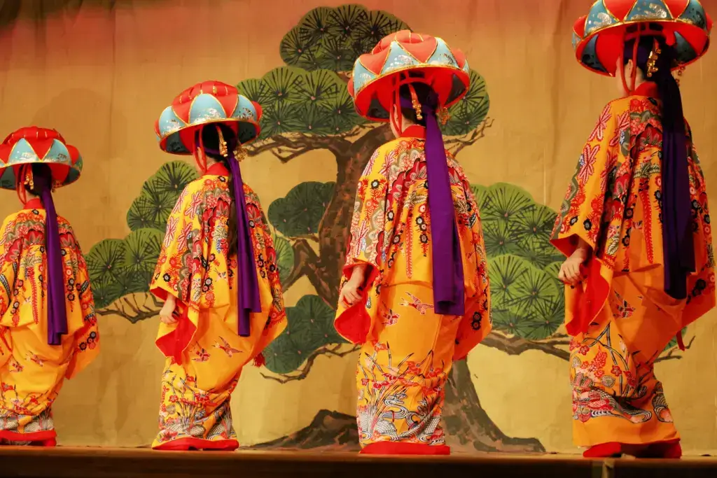 A bunch of women in a traditional Ryukyu procession, wearing orange ryusou robes.