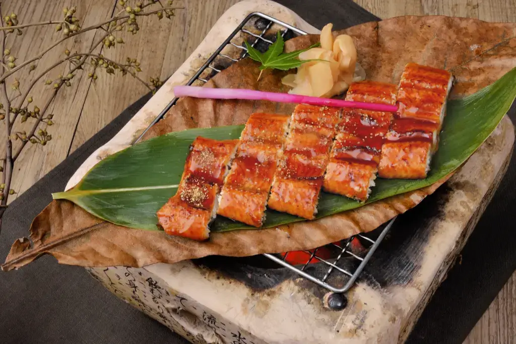 Slices of unagi on a large green leaf.