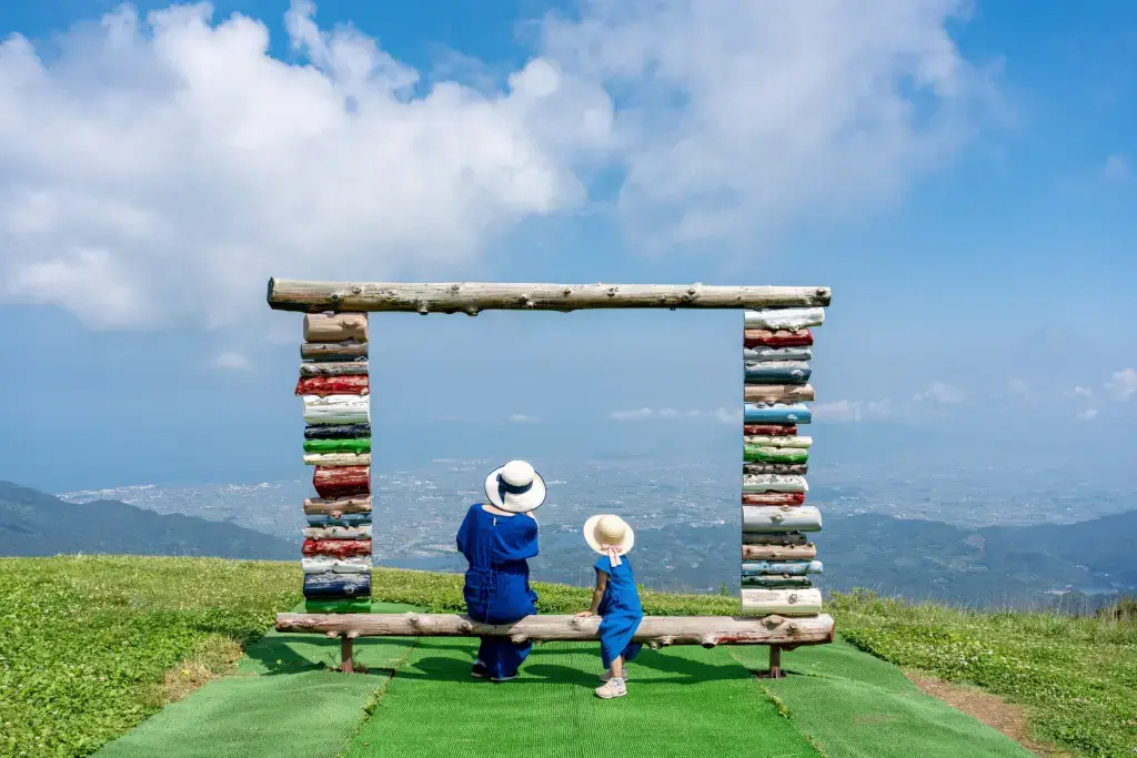 A mother and child standing under a stone sculpture in Kagawa Prefecture.