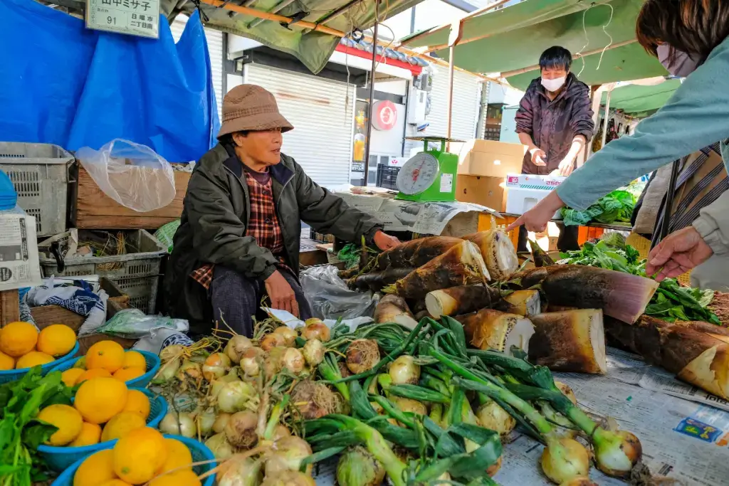 A woman selling vegetables at the Sunday Market in Kochi Japan.