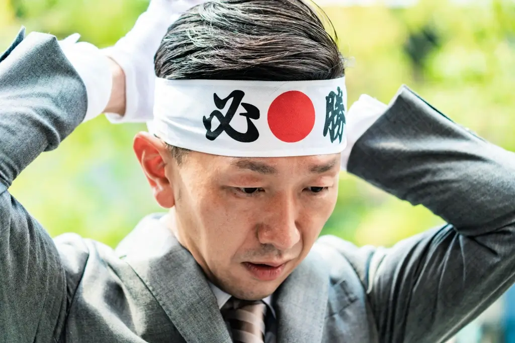 A man wearing a hachimaki (a bandanna) with the word for "certain victory" on it.