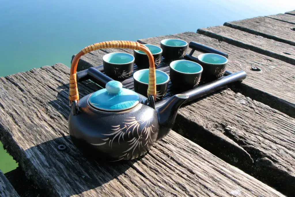 A teapot with matching teacups on a deck.