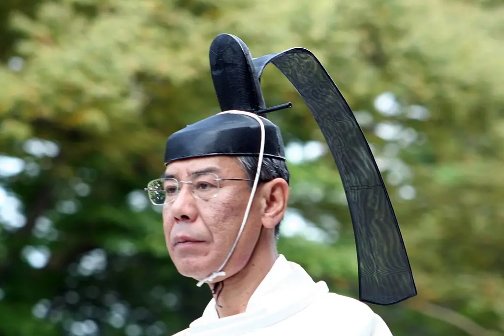 An elderly man wearing a kanmuri (tall black Japanese crown). It somewhat resembles a hat.