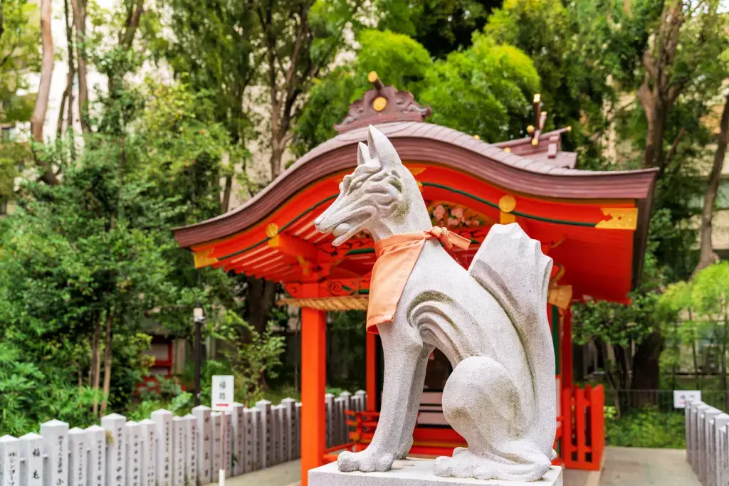 A ktisune statue at a shrine wearing an orange bib.