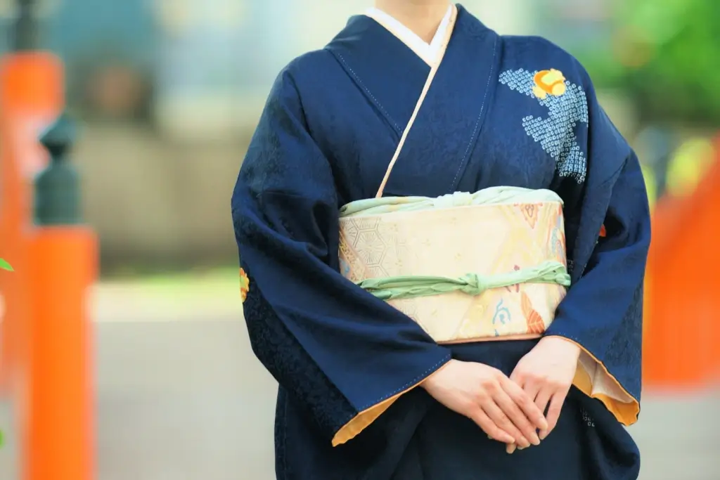 A woman wearing a navy kimono with a cream-colored obi.