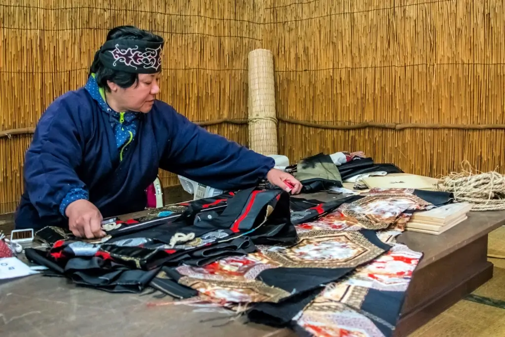 An Ainu woman making clothes at the open air museum.