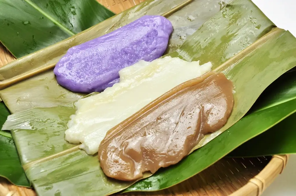 Three different colored muchi (rice cake) on a large leaf.