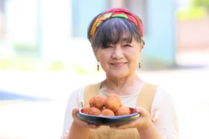 A woman holding a plate of sata andagi doughnuts.