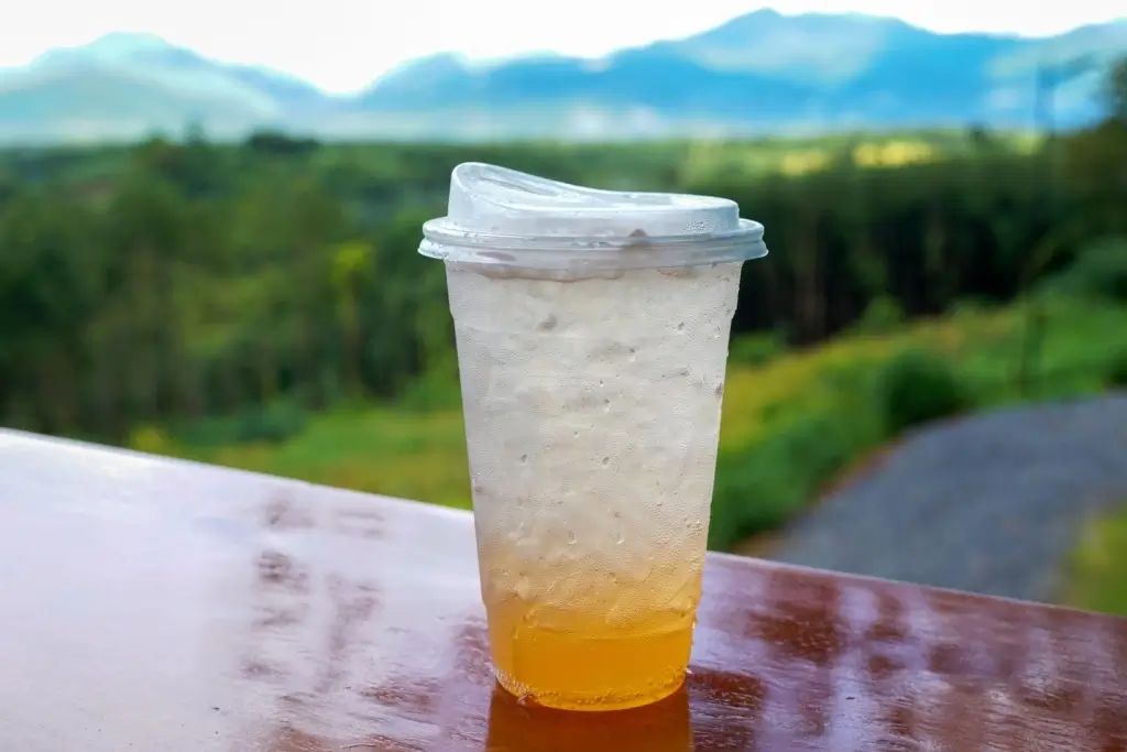 A cup of yuzu soda sits on a deck overlooking mountains in Japan.