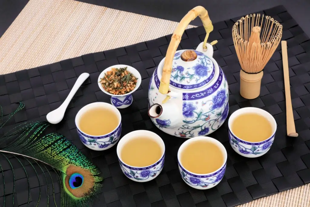 A pot of roasted brown rice tea surrounded by cups of tea.