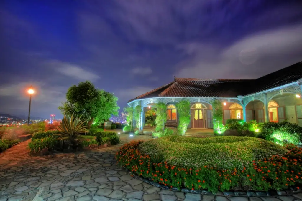 Glover Garden at night, featuring palm trees and tropical bungalow.