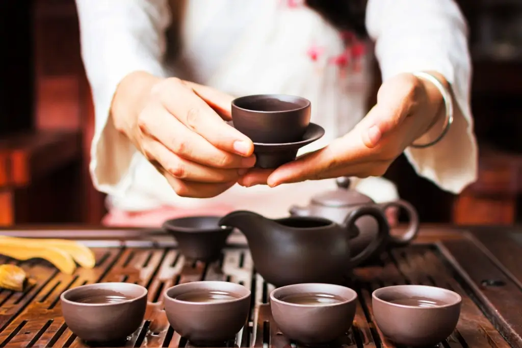 Someone using Japanese ceramics in the form of black teacups.