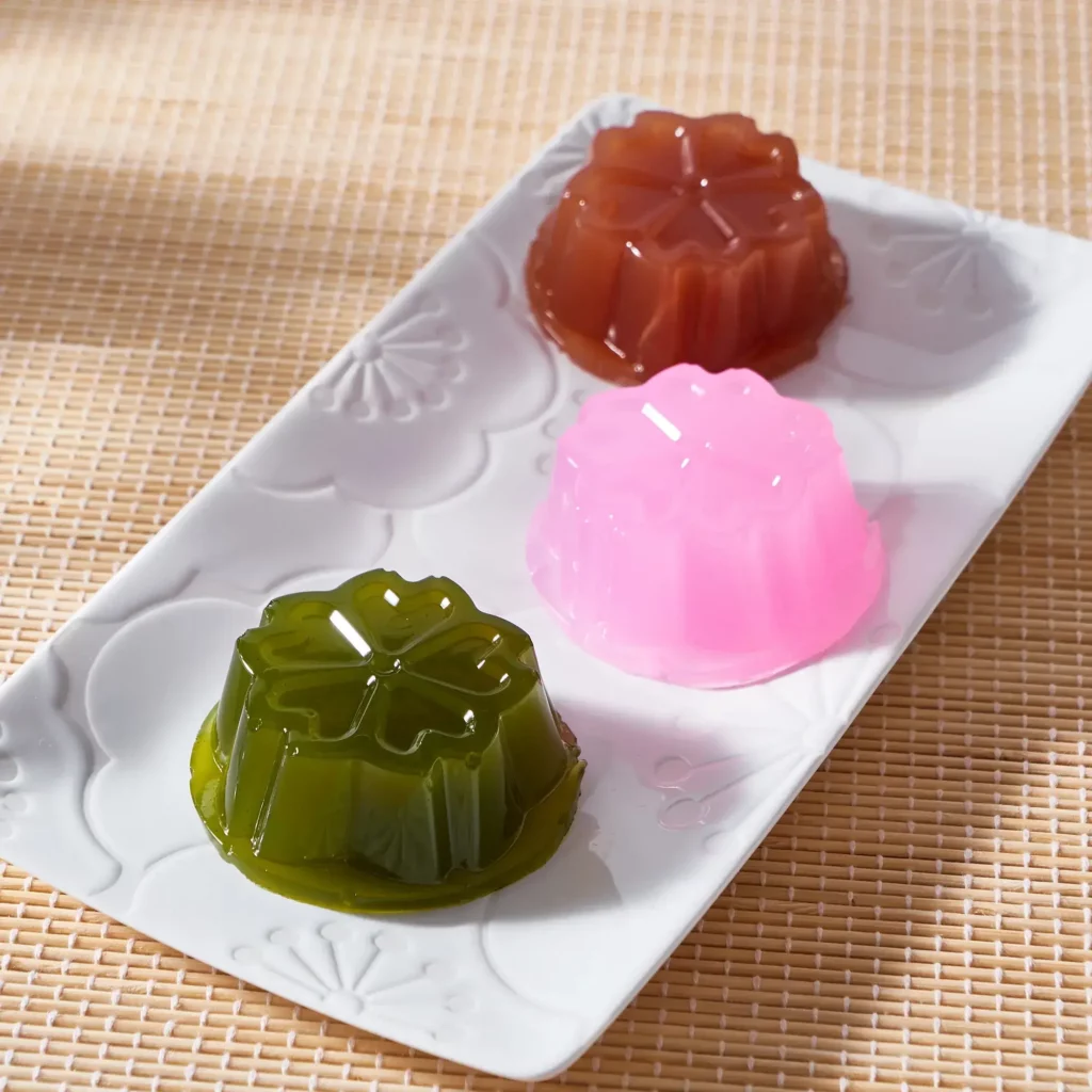 A plate of different colored kuzumochi: brown, pink and green, respectively.