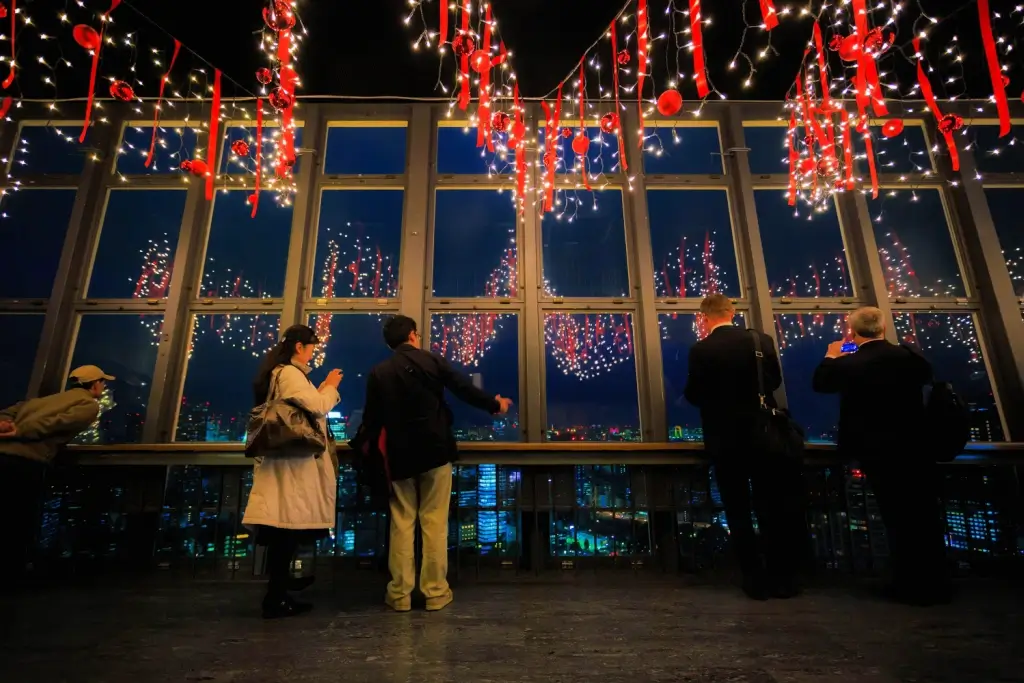 A bunch of people at a holiday party with red ribbons and decorations.