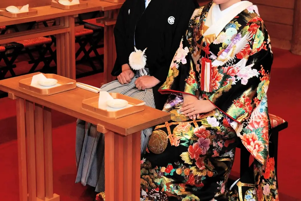 A married couple sitting in front of a table with two cups of sake.