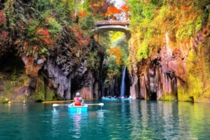 Two people riding kayaks among cliffs in the Kyushu region.