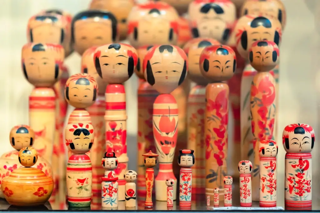 A collection of Kokeshi no Okajin kokeshi dolls. They're long, thin red with a large head.