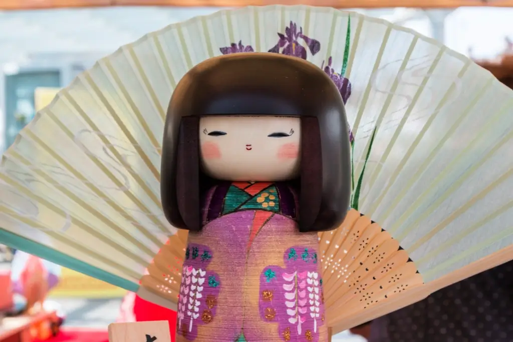 An Usaburo Kokeshi doll. It's purple with a large black hair shape.